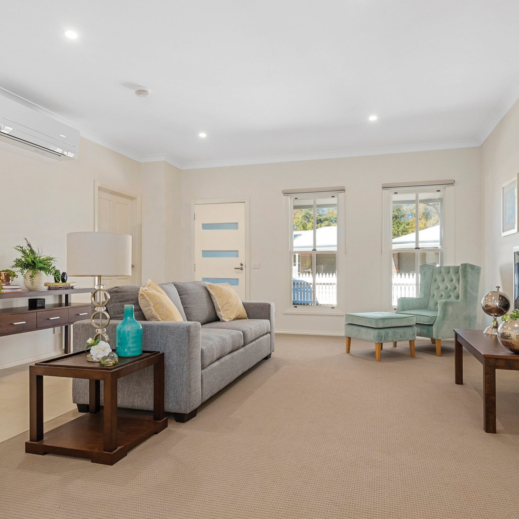 Image of a living area with a grey couch and light green armchair with a footrest